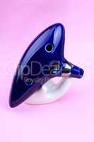 Blue Ceramic Ocarina with stand on pink background