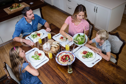 Happy family talking to each other while having meal in kitchen