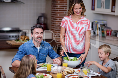 Woman serving food to her family in the kitchen