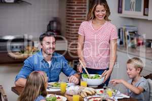 Woman serving food to her family in the kitchen