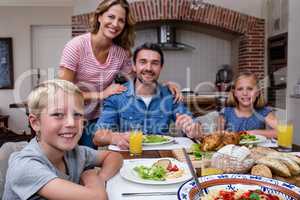 Portrait of happy family having meal in kitchen