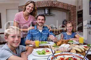 Portrait of happy family having meal in kitchen