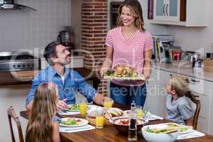 Woman serving food to her family in the kitchen