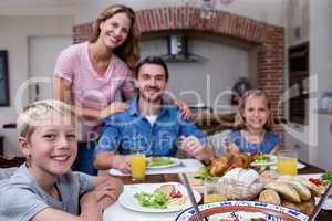 Portrait of happy family having meal in kitchen