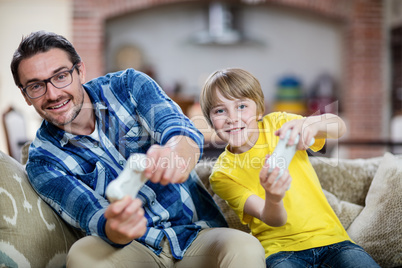 Father and son playing video game on sofa