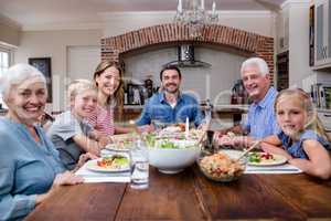 Multi-generation family having meal in kitchen