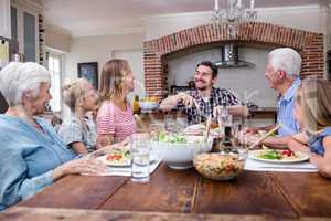 Man cutting roasted turkey while having meal with his family