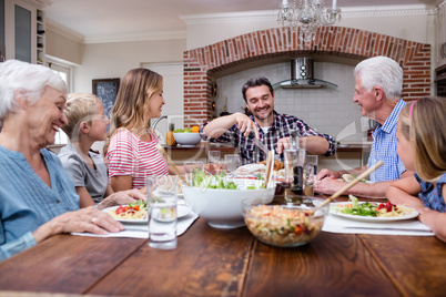 Man cutting roasted turkey while having meal with his family