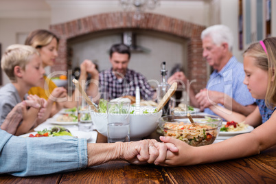 Multi-generation family praying before having meal