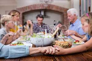 Multi-generation family praying before having meal