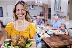 Portrait of happy woman holding a tray of roasted turkey