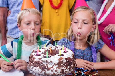 Siblings blowing the candles at birthday party