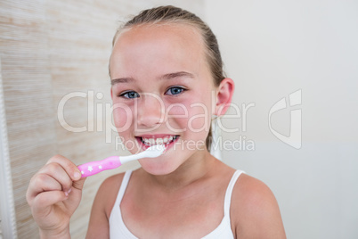 Happy girl brushing her teeth in bathroom