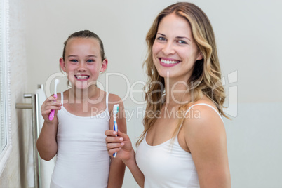 Portrait of happy daughter and mother holding a toothbrush in th