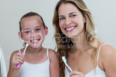 Portrait of happy daughter and mother holding a toothbrush in th