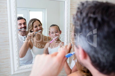 Parents and daughter brushing their teeth in the bathroo