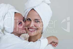 Girl in bathrobe kissing her mother