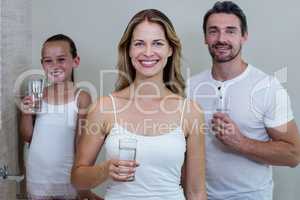 Parents and daughter holding a glass of water in bathroom
