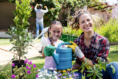 Mother and daughter holding a watering can while gardening