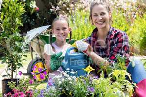 Mother and daughter holding a watering can while gardening