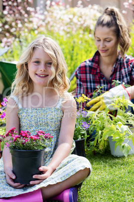 Portrait of girl sitting in garden with flower pot