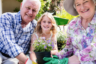 Portrait of grandparents and granddaughter holding flower pot