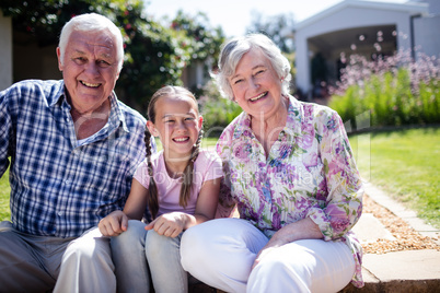 Grandparents and granddaughter sitting in the garden