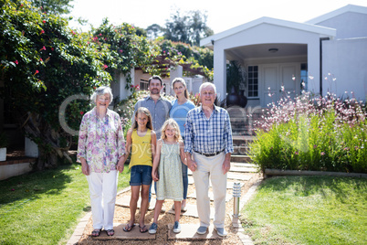 Multi-generation family standing on the garden path