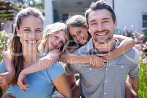 Portrait of parents giving a piggy back to daughters