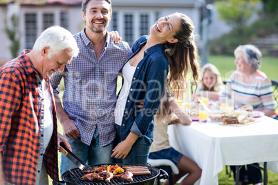 Couple and a senior man at barbecue grill preparing a barbecue