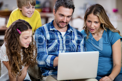 Parents and kids sitting on sofa and using a laptop