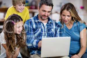 Parents and kids sitting on sofa and using a laptop