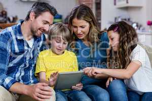 Parents and kids sitting on sofa and using a digital tablet