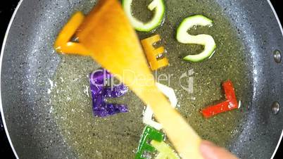 Stir-frying mixed alphabet letters, word Vegetables