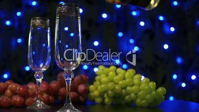 Bubbling champagne being poured into two crystal glasses against boke black backgroung