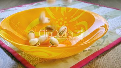 Pistachio nuts falling into bowl, slow motion