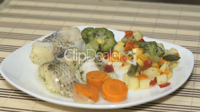 Macrourus fish with vegetables on the white plate
