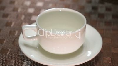 Pouring black tea in a white porcelain mug