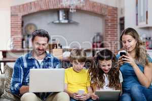 Parents and kids using a laptop, tablet and phone