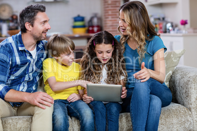 Parents and kids sitting on sofa and using a digital tablet