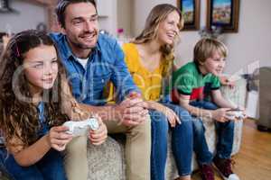 Family sitting on sofa and playing video game