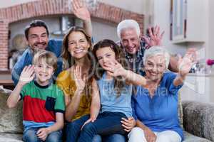 Portrait of multi-generation family sitting on sofa and waving h