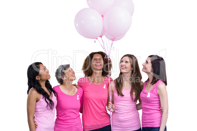 Smiling women in pink outfits posing with balloons for breast ca