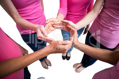 Women in pink outfits joining in a circle for breast cancer awar