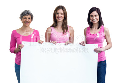 Women in pink outfits holding board for breast cancer awareness