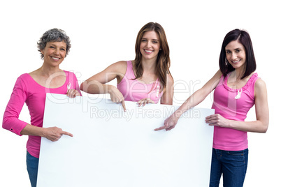 Women in pink outfits holding board for breast cancer awareness