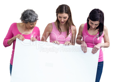 Women in pink outfits holding board for breast cancer awareness