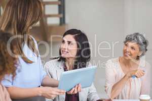 Female business colleagues discussing on digital tablet