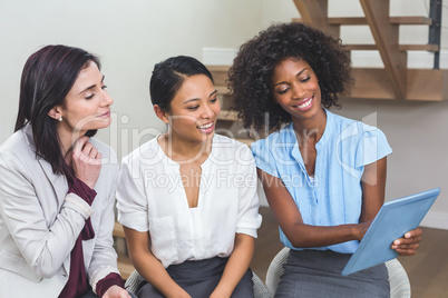 Female business colleagues discussing on digital tablet