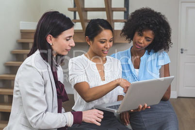 Female business colleagues discussing on laptop